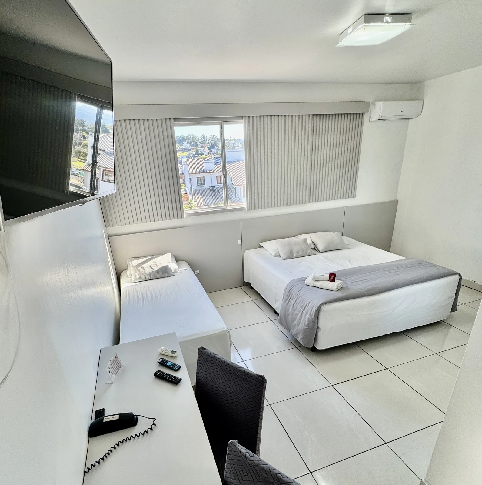 Quarto com cama de casal, cama de solteiro e mesa de trabalho